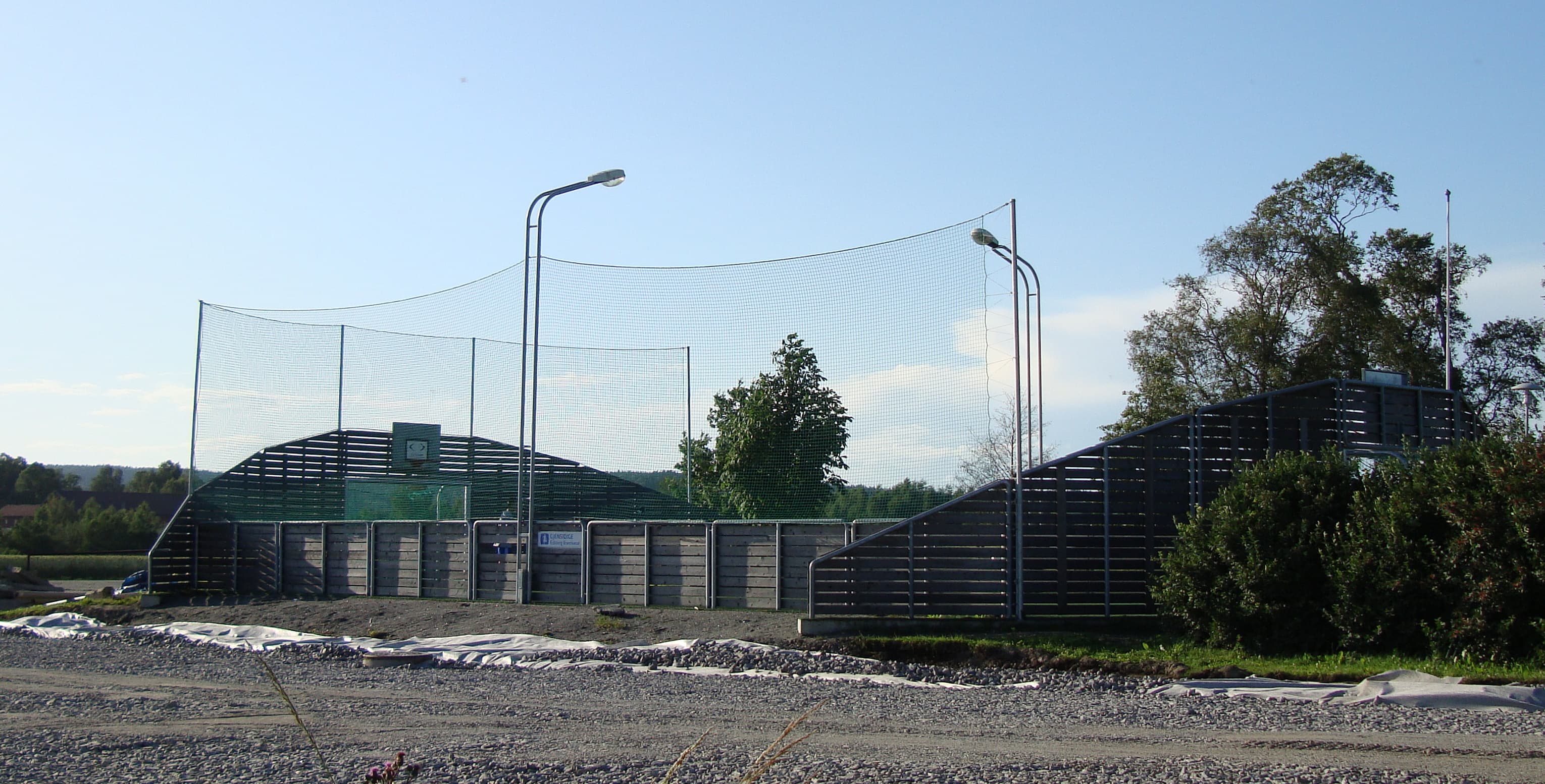 Innhegnet ballbinge med nett og lysmaster.