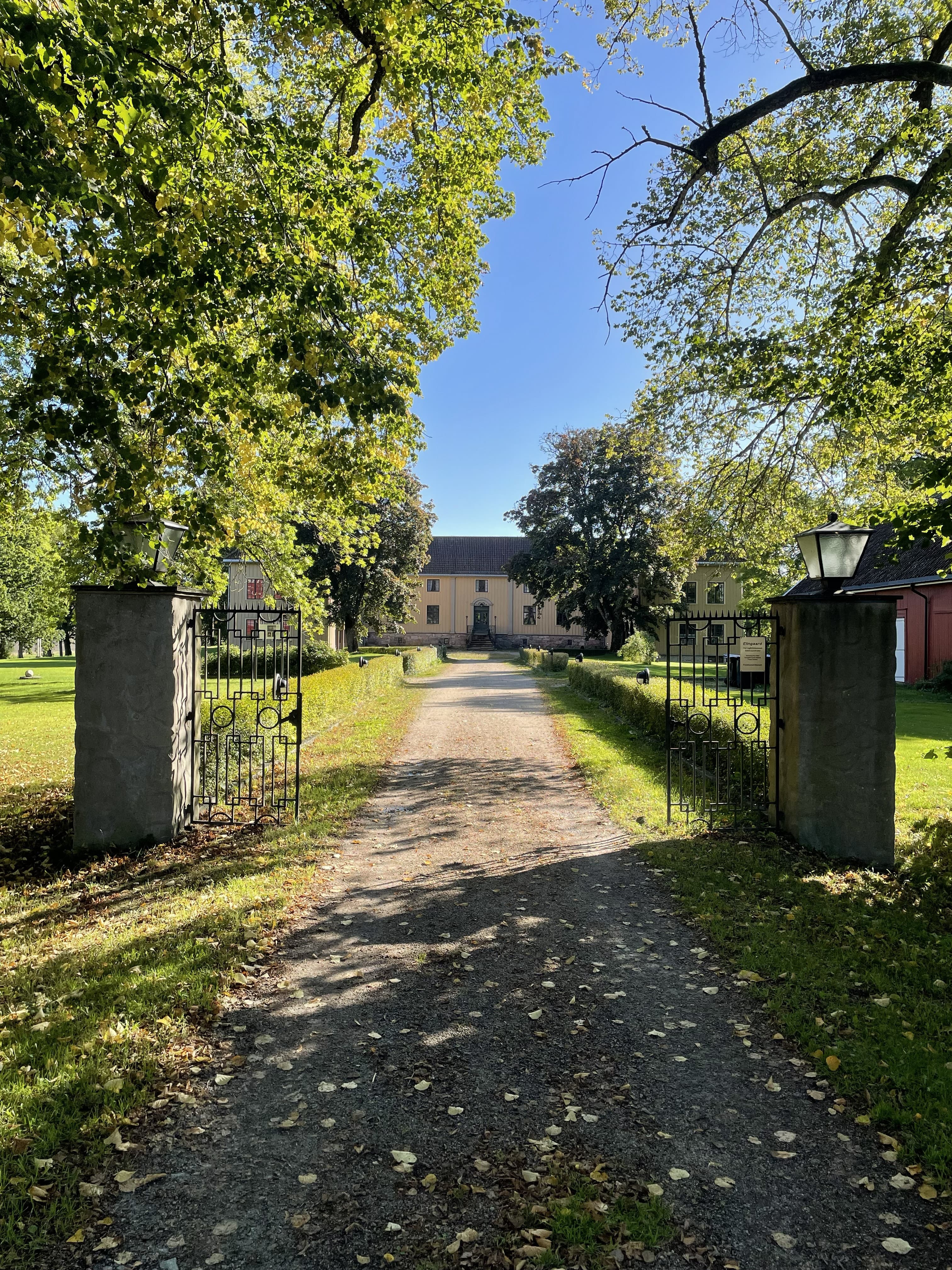 Innkjørselen til Elingård herregård gjennom smijernsporten, med den gule hovedbygningen i enden av alleen.
